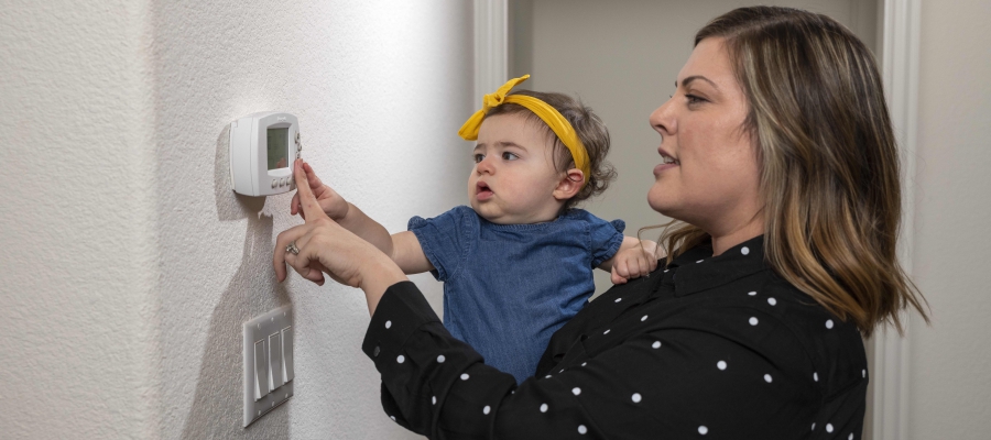 mom and baby adjust thermostat