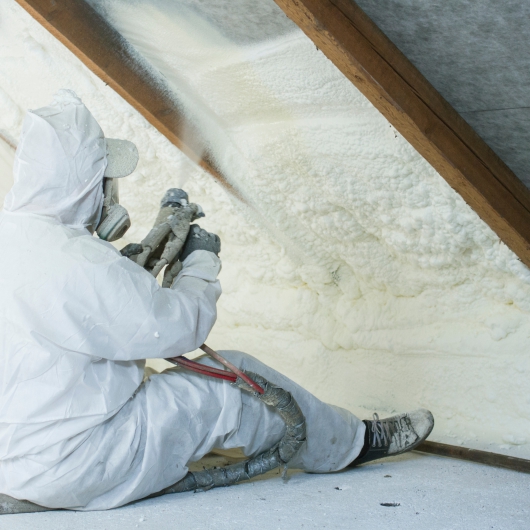 Man sprays insulation in attic